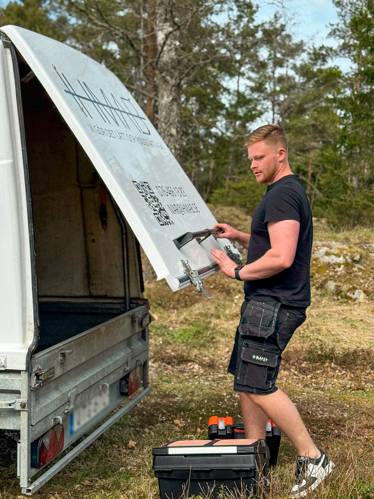 Ivar Hellström gör sig redo att sköta nästa fastighet. Han har precis plockat ut sina verktyg ur sitt släp, dekorerat med IHMAB.