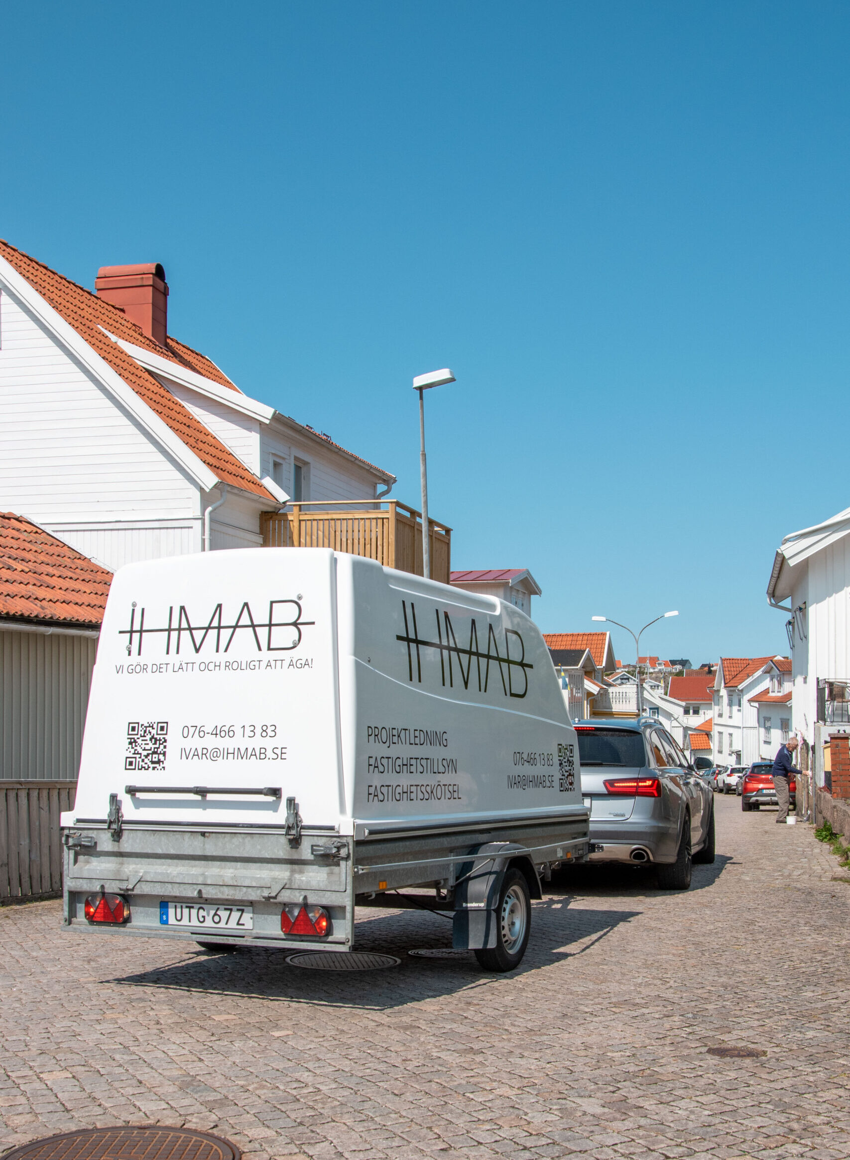 IHMAB:s släpvagn med tydlig företagsprofil i ett bostadsområde – symbol för professionell fastighetstillsyn, effektiv fastighetsskötsel och pålitlig projektledning inom trygg fastighetsförvaltning i lokala miljöer.